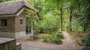 Una casa rústica con techo de paja, rodeada por un bosque frondoso.