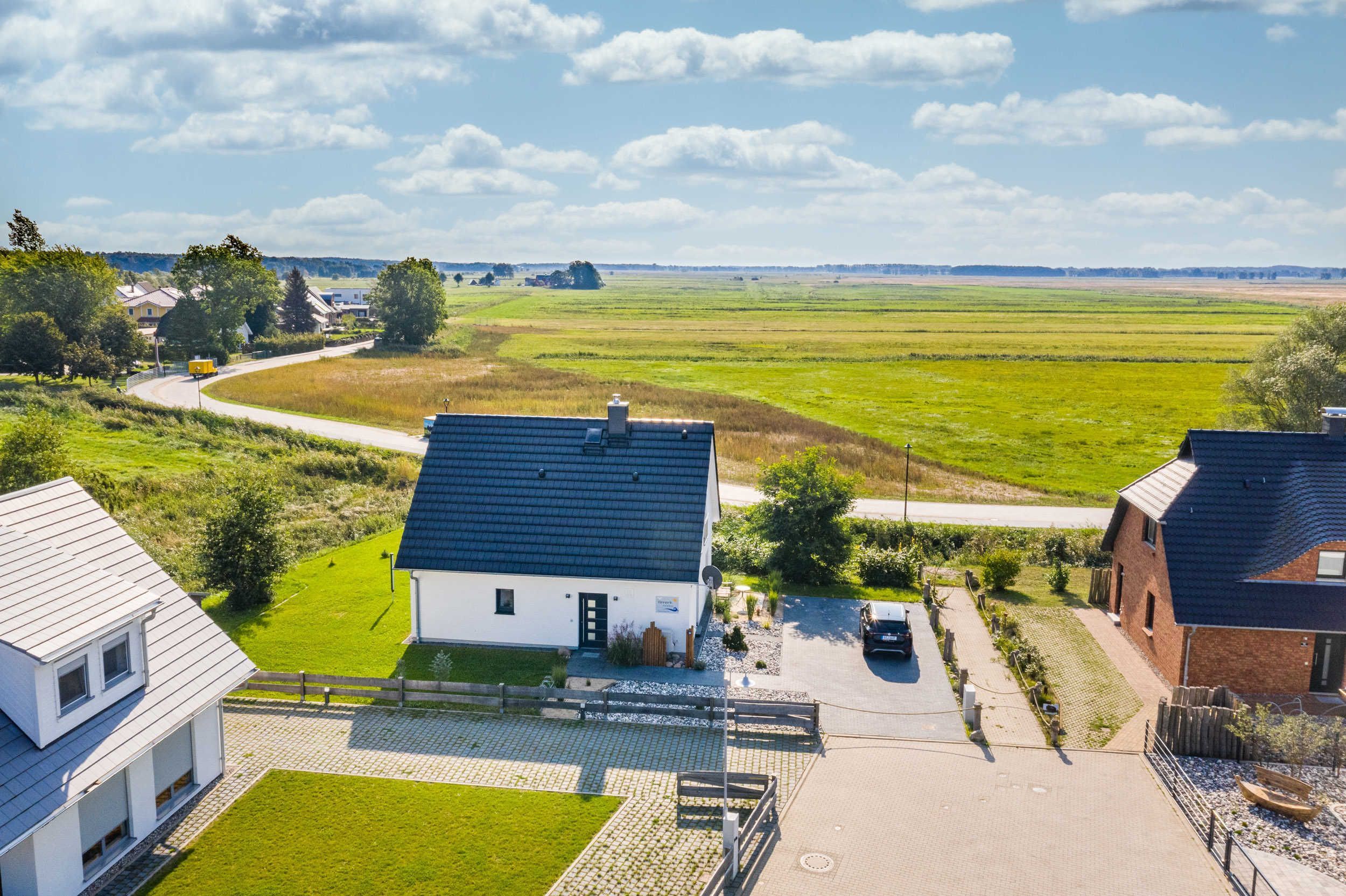 A residential area with houses, a paved driveway, and a green field.