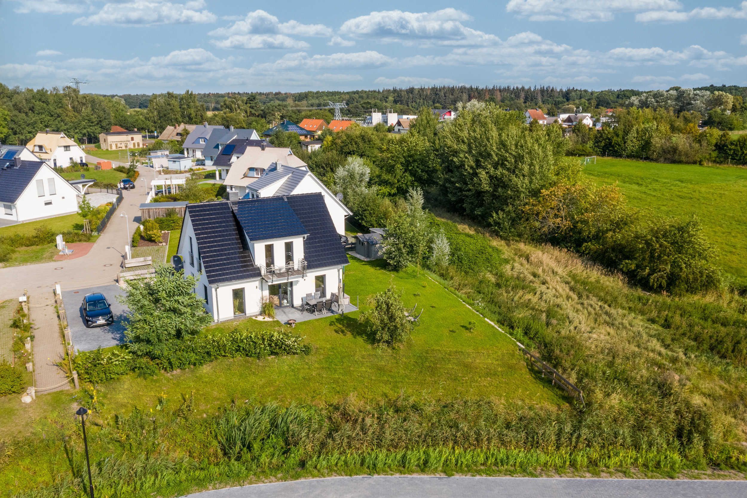 Ein Wohngebiet mit Häusern, einer Straße und einem grünen Feld.