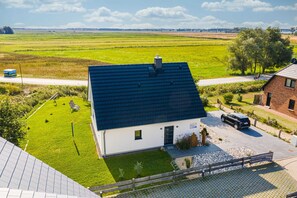 A house with a dark roof, a small front yard, and a paved driveway.