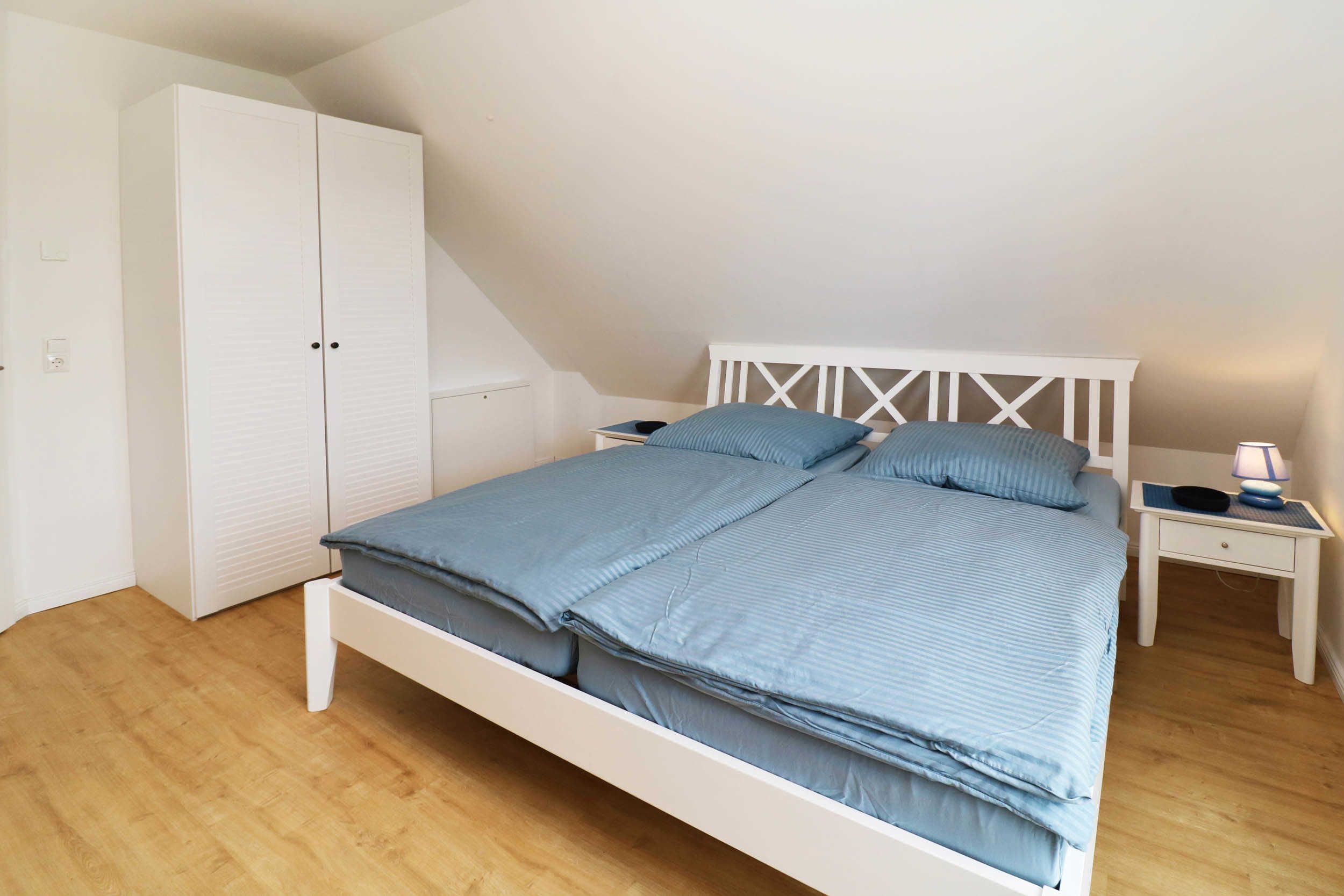 Een slaapkamer met een bed, een kast, een nachtkastje en een lamp.