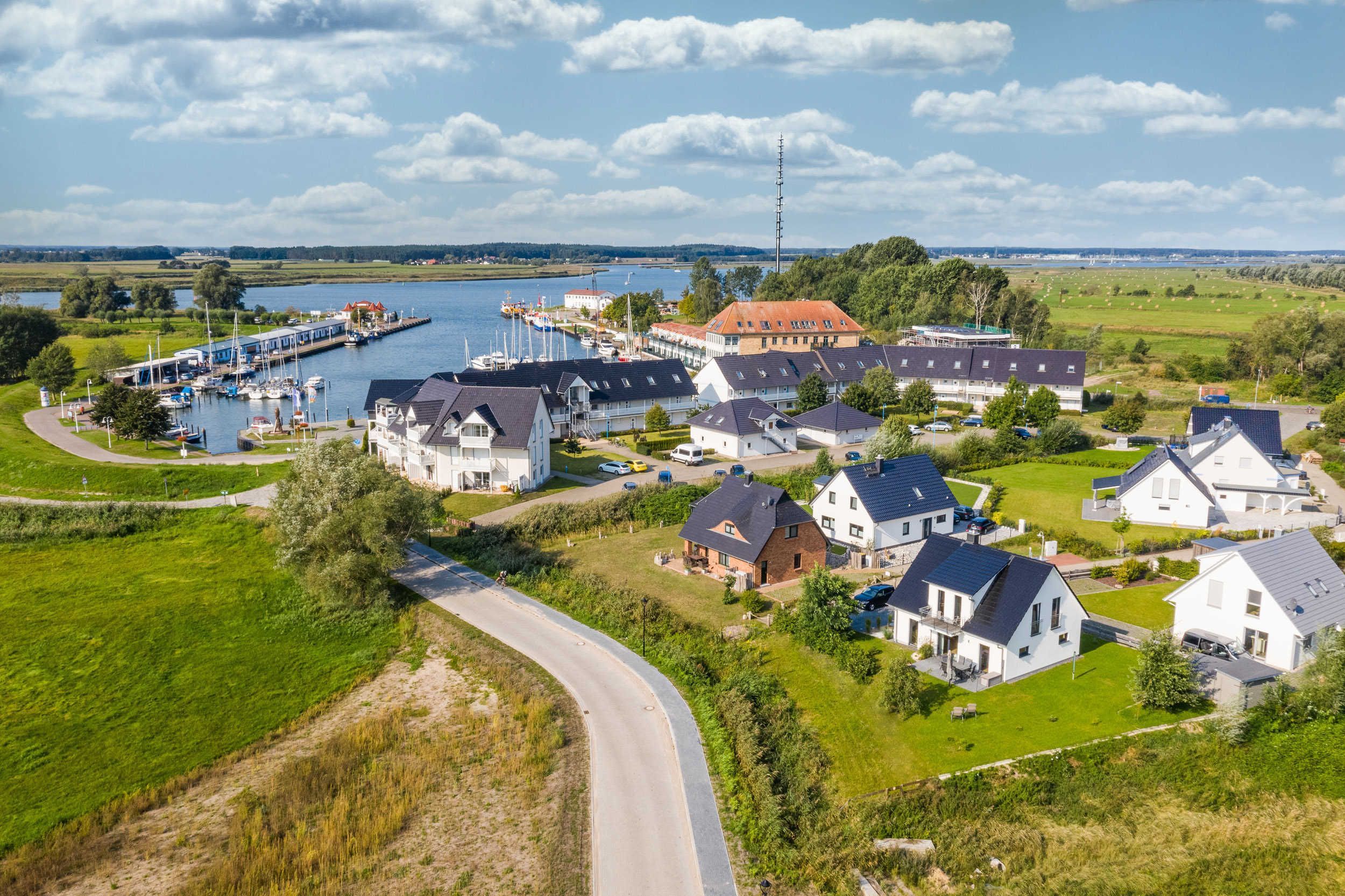 Een kustdorp met huizen, een jachthaven en een groot gebouw met een rood dak.