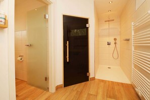 Einladender Saunabereich im Ferienhaus Hinnerk in Karlshagen auf der Insel Usedom mit moderner Holzsauna, Dusche und WC.