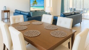 Ein Essbereich mit einem Holztisch, weißen Stühlen und gewebten Platzsets.