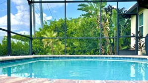 Ein Pool mit Blick auf üppige Grünanlagen und ein modernes Gebäude.