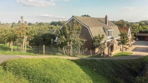 Une maison avec un toit en pente, entourée d’une cour clôturée et d’un petit jardin.