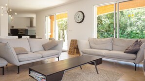 A modern living room with two sofas, a coffee table, and a large window with a view of greenery. - Pet friendly home in Bédarieux (Bédarieux)