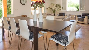 A dining area with a rectangular table, six chairs, a vase with red flowers, and a clock on the wall. - Pet friendly home in Bédarieux (Bédarieux)