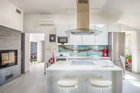 Enjoy cooking in this kitchen with a sleek island, appliances, and a decorative backsplash.