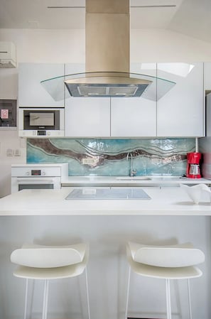Enjoy casual dining and socializing in this kitchen with a microwave, coffee machine, and wavy backsplash.