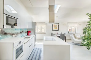 Enjoy cooking in this well-lit kitchen with sleek cabinetry, a refrigerator, and a unique backsplash.