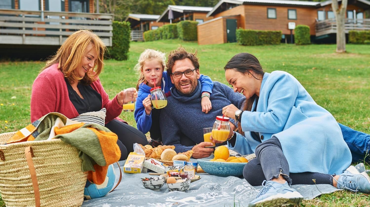 A group of people having breakfast outdoors with a picnic setup.
