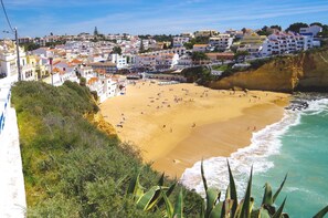 A coastal town with a sandy beach, buildings along the cliff, and a view of the sea.