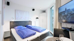 Habitación de hotel con cama, escritorio, televisión y ventana con vista a la ciudad.