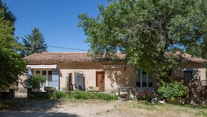 A rustic house with a tiled roof, a front door, and a small porch area. - Comfortable gîte in the heart of the quiet luberon countryside, ideal for families. (Bonnieux)
