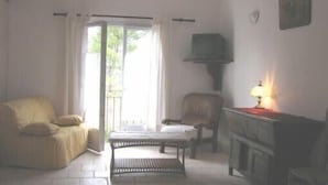 A living room with a sofa, armchair, and a small table. - Comfortable gîte in the heart of the quiet luberon countryside, ideal for families. (Bonnieux)