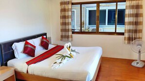 Una habitación de hotel con cama, ventilador y cortinas.