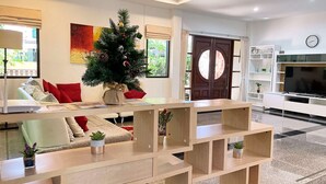 Una sala de estar moderna con un mueble de madera para entretenimiento, un árbol de Navidad y un sofá con cojines rojos.