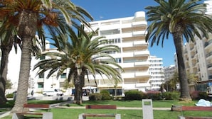A modern building with multiple balconies, surrounded by palm trees and a well-maintained lawn. - Exceptional apartment seafront (Armação de Pera)