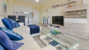 A modern living room with a sofa, glass coffee table, and a TV. - Exceptional apartment seafront (Armação de Pera)