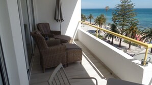 A balcony with wicker furniture, a view of the beach, and a railing. - Exceptional apartment seafront (Armação de Pera)