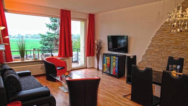 A living room with a sofa, chairs, a TV, and a bookshelf.