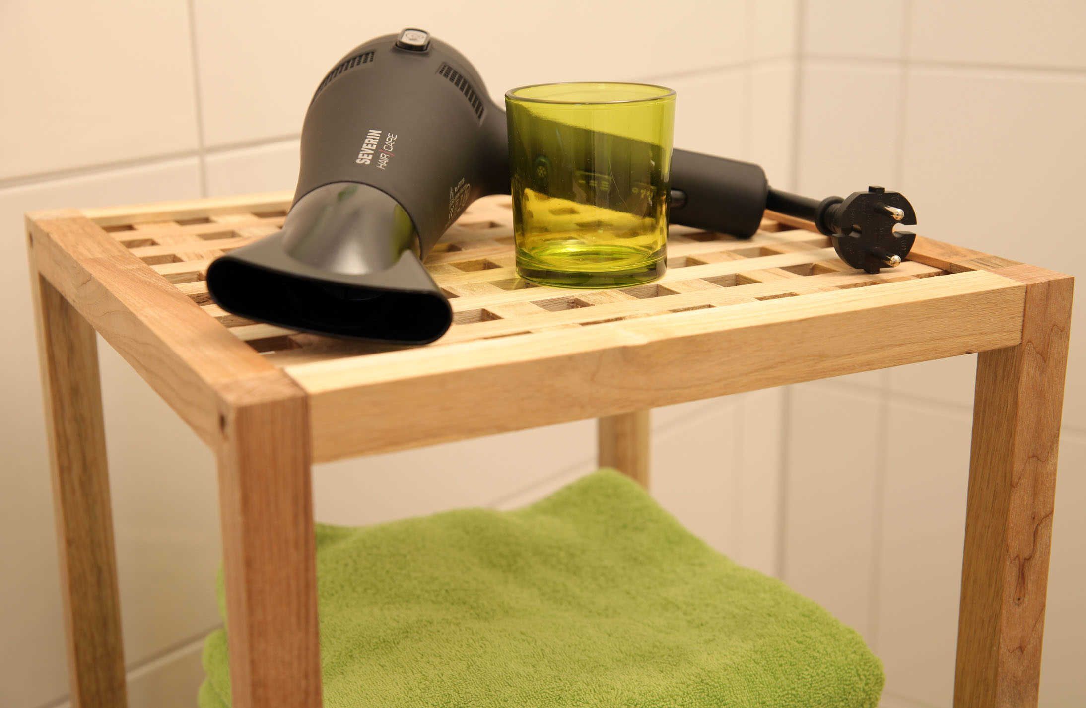 Um secador de cabelo e um copo sobre uma mesa de madeira com uma toalha verde por baixo.