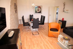 Un salon moderne comprenant un coin repas, un téléviseur et une table basse.