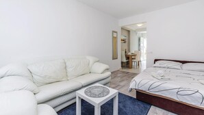 Ett modernt sovrum med en vit soffa, ett litet sidobord och en säng med ett mönstrat överkast.