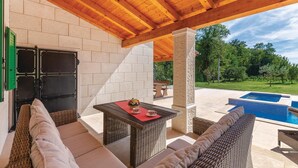 An outdoor patio with wicker furniture, a table with a red placemat, a pool, and a stone wall. - Gorgeous home in Pican (Pican)