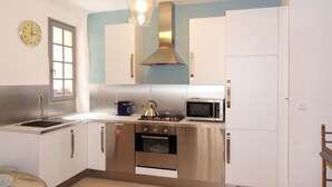 A compact kitchen with a sink, stove, microwave, and cabinets. - L'Appart, charm and confort  (Cotignac)