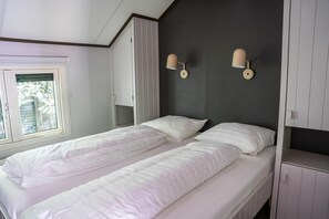 Ein Schlafzimmer mit zwei Einzelbetten, einem Fenster mit Jalousien, einem Kleiderschrank und zwei Wandleuchten.