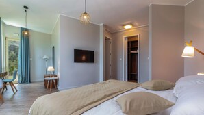 A modern hotel room with a large bed, a TV, a wardrobe, and a view of the outdoors. - Amazing home in Veprinac with sauna (Veprinac)