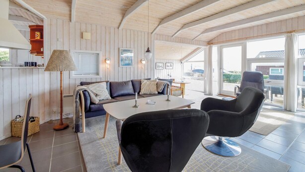 A cozy room with a wooden ceiling, a sofa, a table, and a chair.