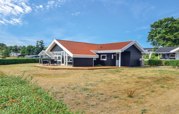 A modern house with a red-tiled roof, a covered patio, and a well-maintained lawn.