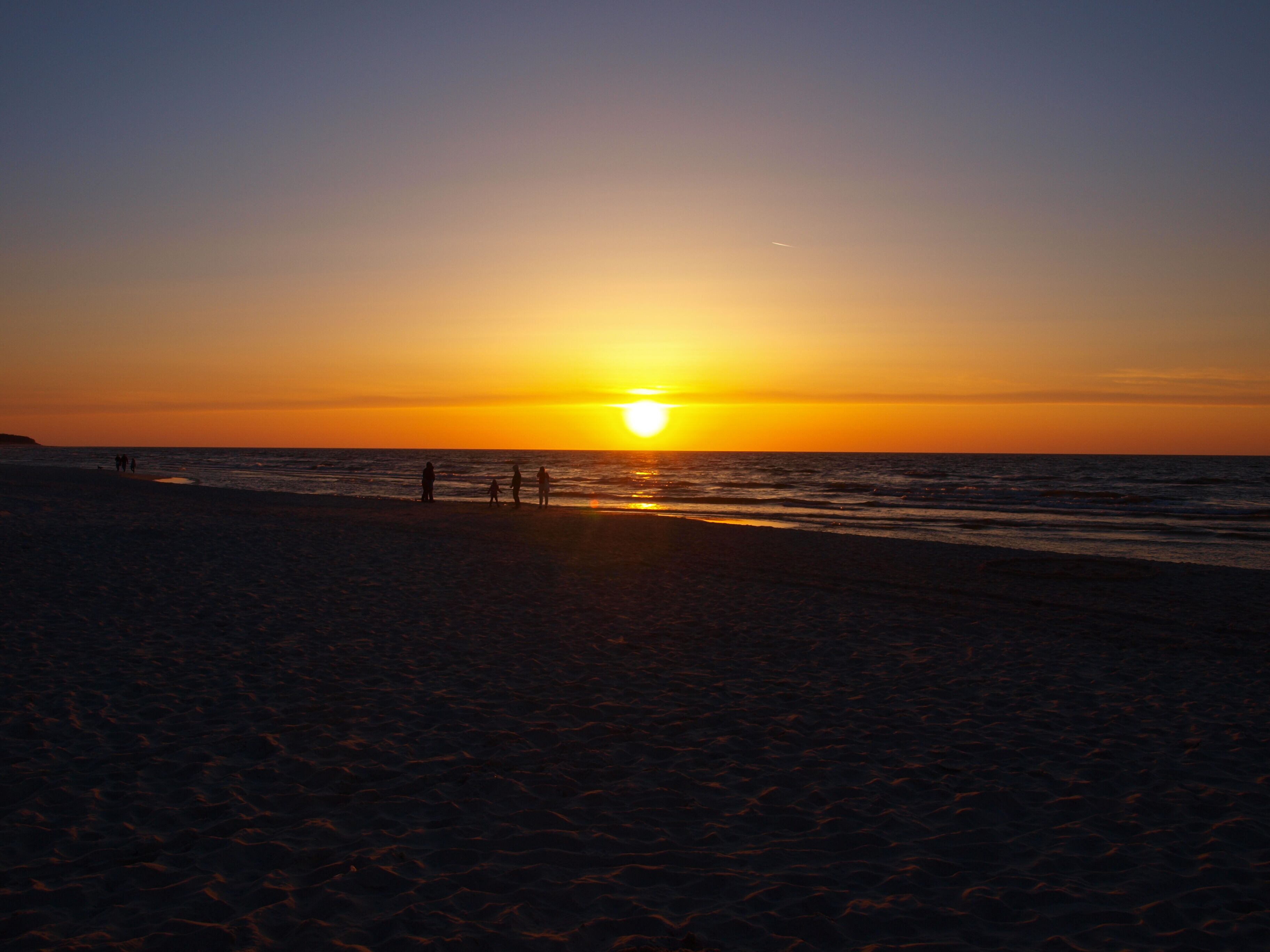 A beach at sunset with a clear sky.