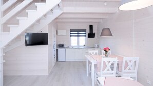A modern kitchen with white cabinetry, a flat-screen TV, and a dining area with a table and chairs. - The newly built "White Cottage Lux", Grzybowo in Um Kolberg, 1-6 persons (Grzybowo)