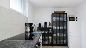 Cozinha compacta com bancada preta, fogão embutido, micro-ondas e geladeira.