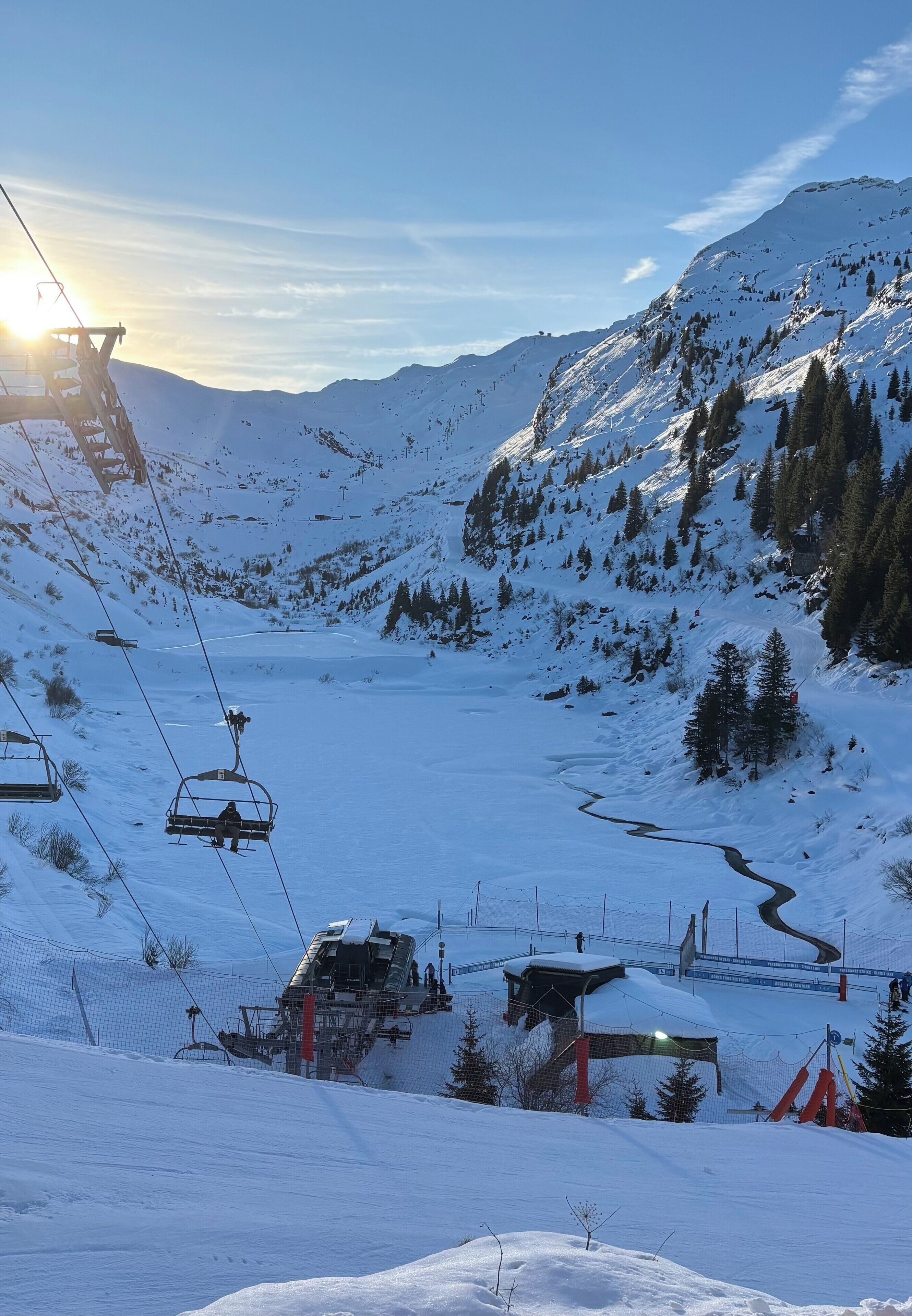 A snow-covered mountain landscape with a ski lift, a small cabin, and a clear sky.