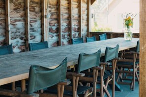 A rustic wooden table with matching chairs, set against a stone wall. - Group farm for 20 people (Voorthuizen)