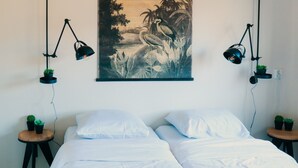 A bedroom with two beds, a wall-mounted painting, and two black desk lamps. - Group farm for 20 people (Voorthuizen)