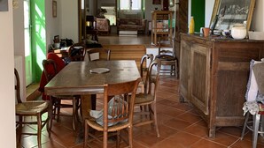 Un comedor con una mesa y sillas de madera, una araña y vista a otra habitación con un sofá y una ventana.