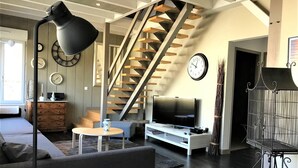 A modern living room with a staircase, a TV, and a sofa. - The clock Chalain 2 (Doucier)