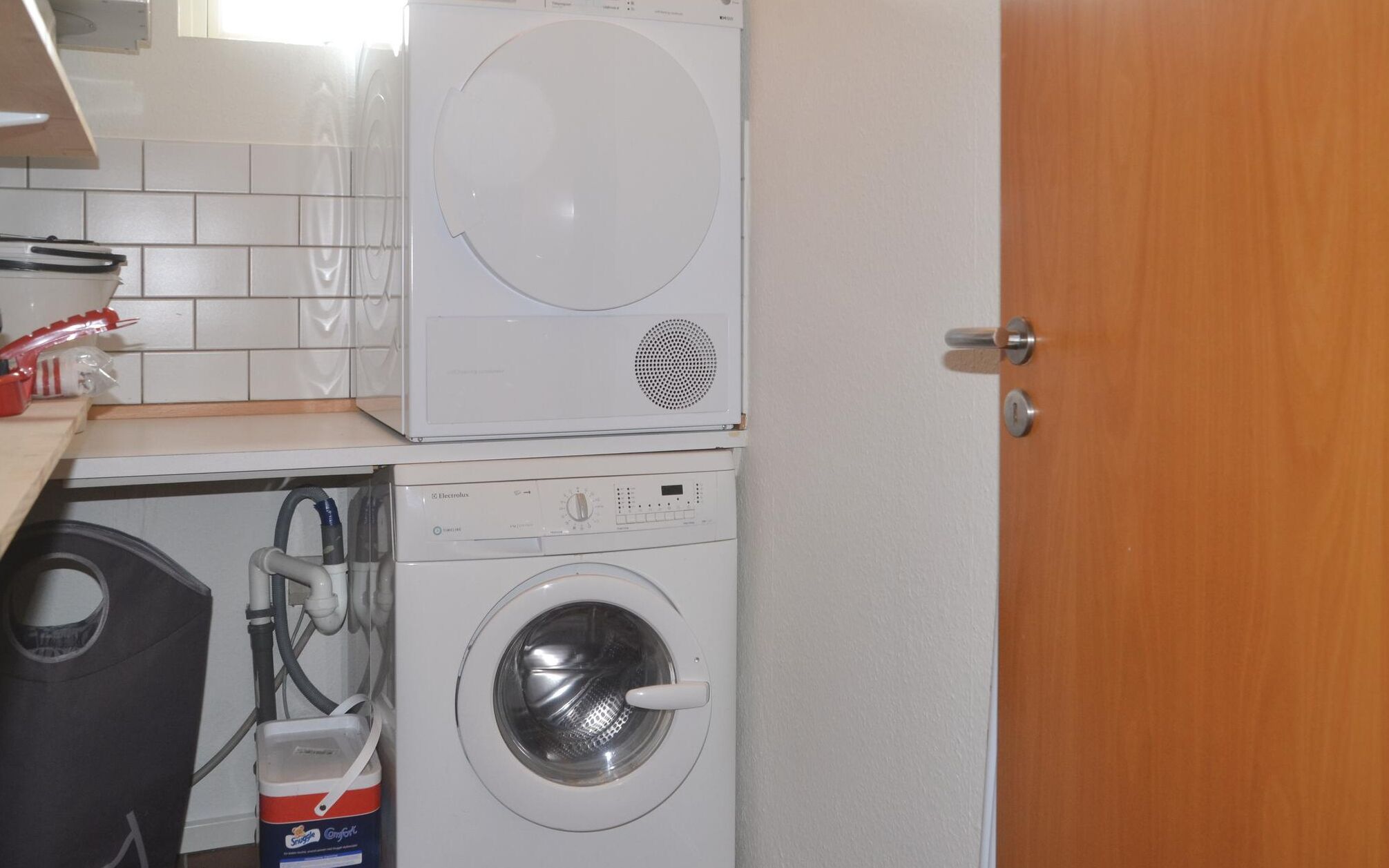 Ein kleiner Waschraum mit einer Waschmaschine mit Oberlader und einem Trockner mit Frontlader.