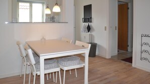 A dining area with a white table and chairs, a window with a view, pendant lights, and a radiator. - 1 bedroom cozy apartment in Varde (Varde)