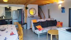 Una sala acogedora con un sofá, una mesita y una cocina equipada con refrigerador y estufa.