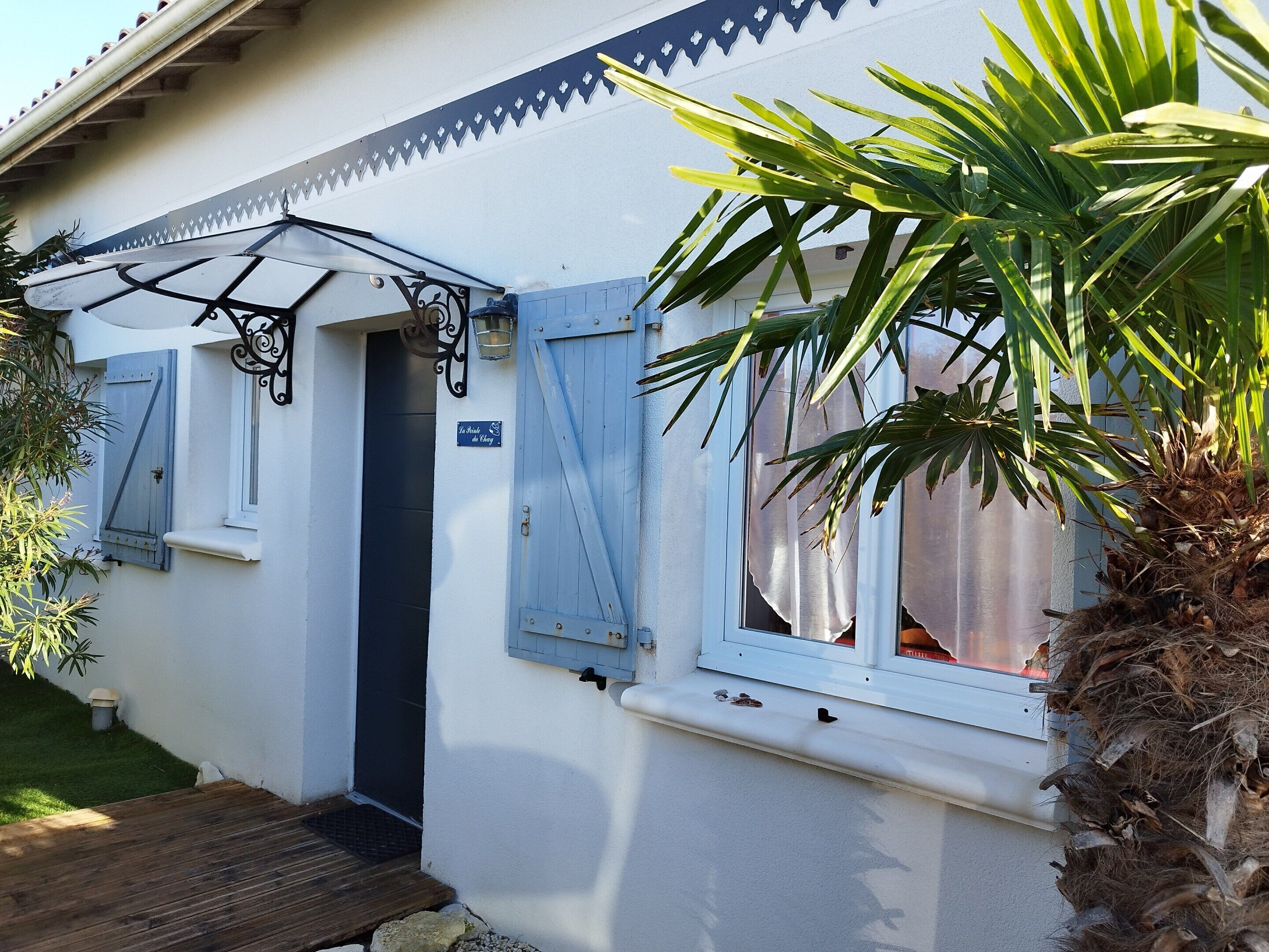 A house with a blue door, a small porch, and a sign that reads "La Maison du Chêne."