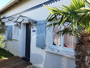 Une maison avec une porte bleue, un petit porche et une enseigne sur laquelle on peut lire : « La Maison du Chêne ».