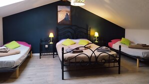 Un dormitorio acogedor en el ático, con techo inclinado, una cama grande con cabecera, dos mesitas de noche con lámparas y un cuadro en la pared.