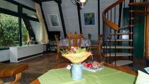 A dining area with a table set for two, a vase with flowers, and a staircase. - Here you will find harmony for the soul and body, garden & house are inviting (Damp)